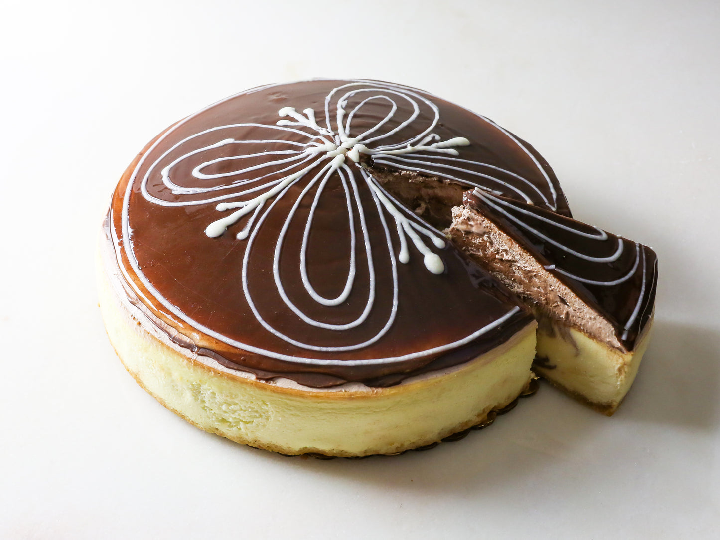 beautifully domed chocolate mousse cheesecake with decorative white glaze on top and slice cut out of side crafted by la roma pastry shop on long island new york