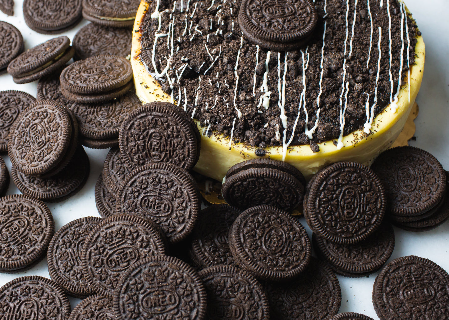 oreo cheesecake from la roma pastry shop in new york with many oreos scattered around and cookies crumbled on top with delicate frosted drizzle