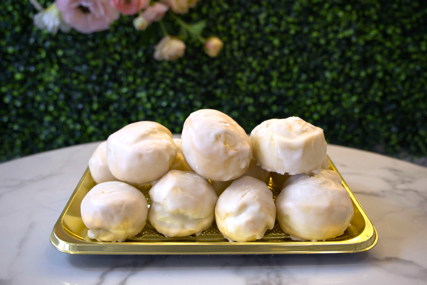 A display of Anginetti cookies from La Roma Pastry Shop in front of floral greenery 