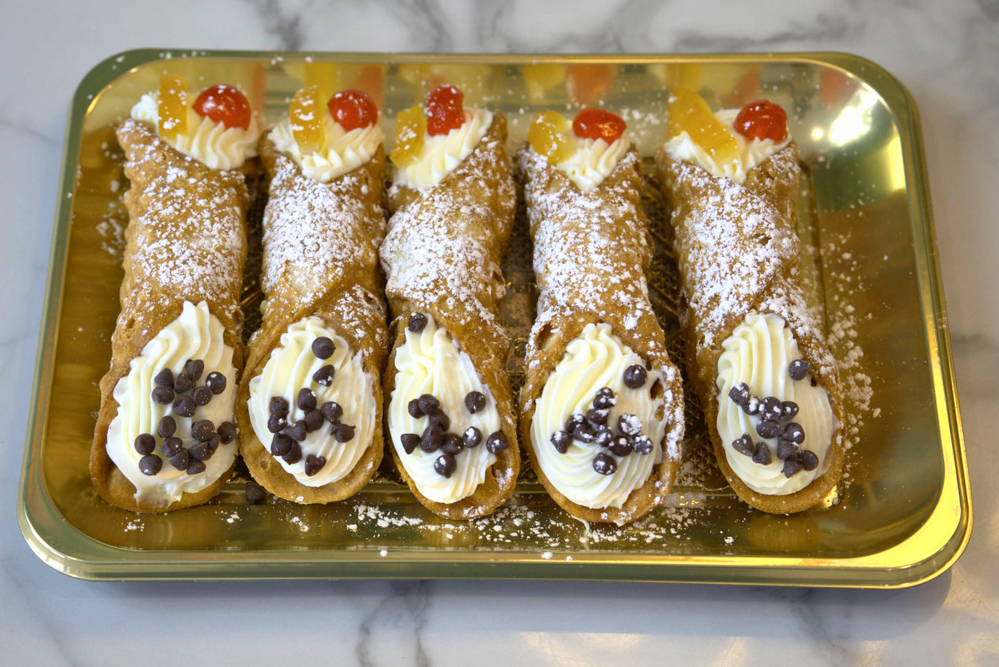 Overhead shot of five cannoli from La Roma Pastry Shop on a golden tray