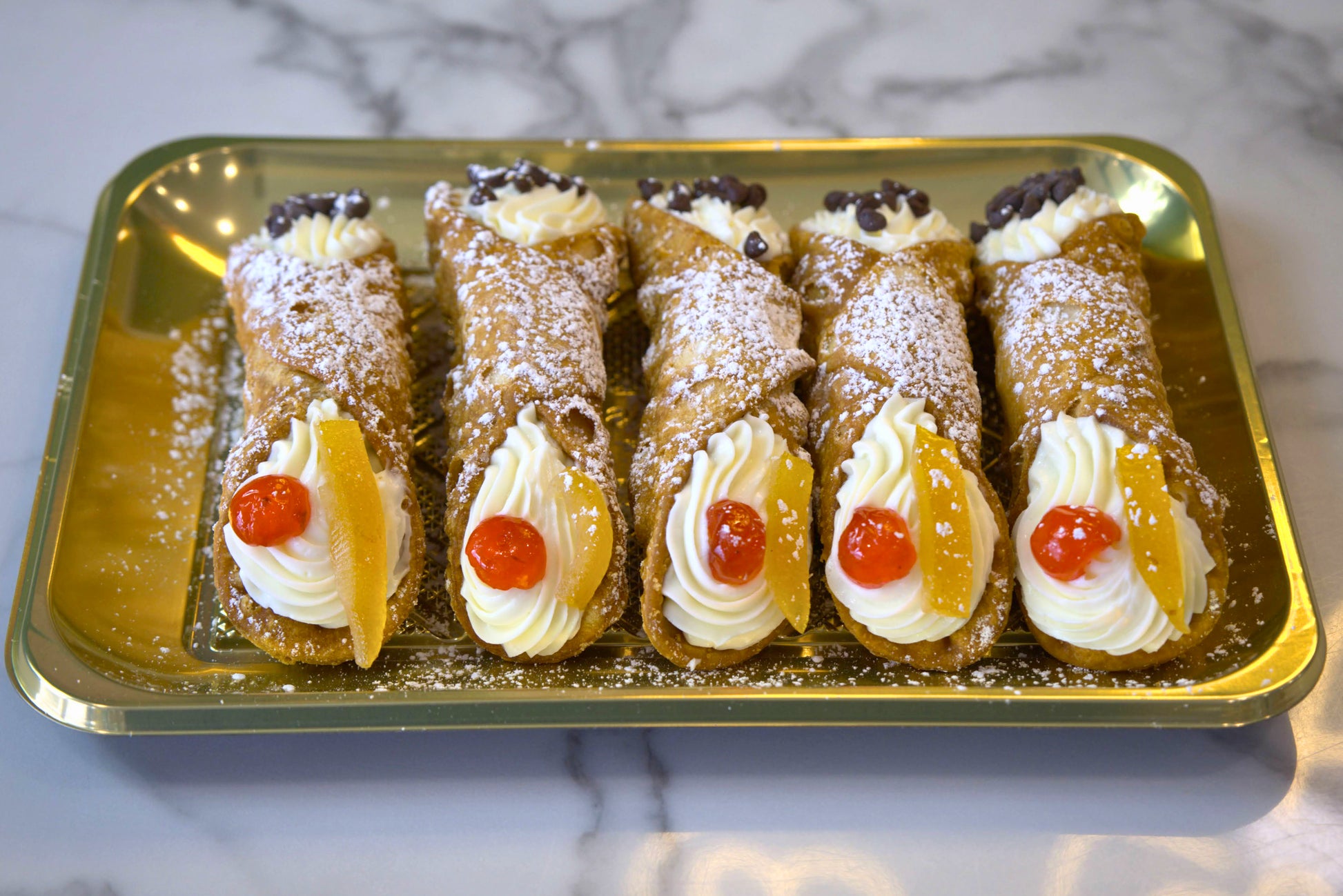Golden tray of five cannoli from La Roma Pastry Shop