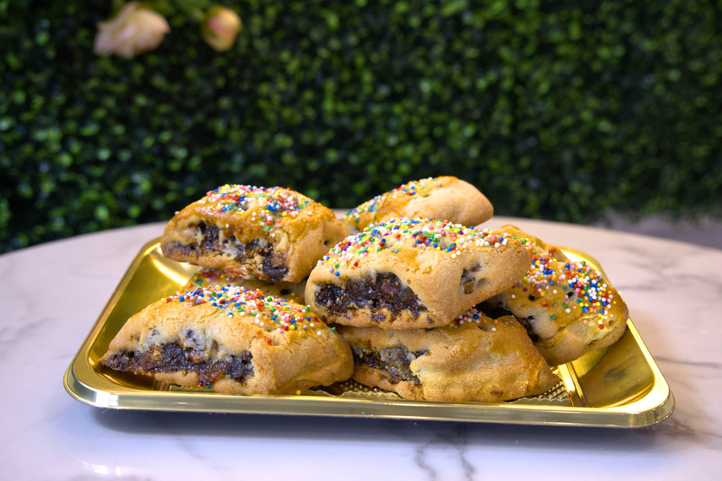A golden tray filled with Cuccidati made by La Roma Pastry Shop