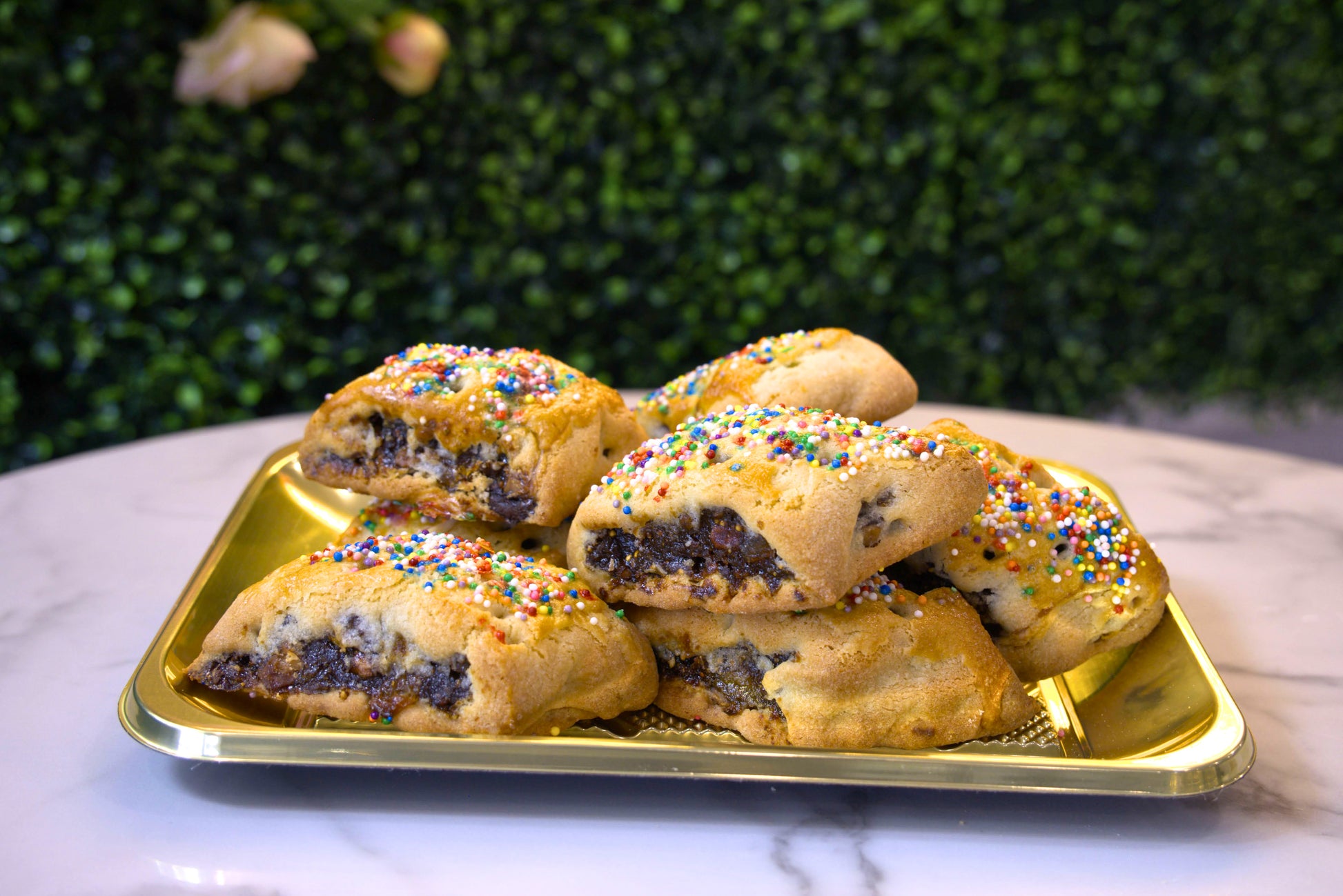 A golden tray filled with Cuccidati made by La Roma Pastry Shop