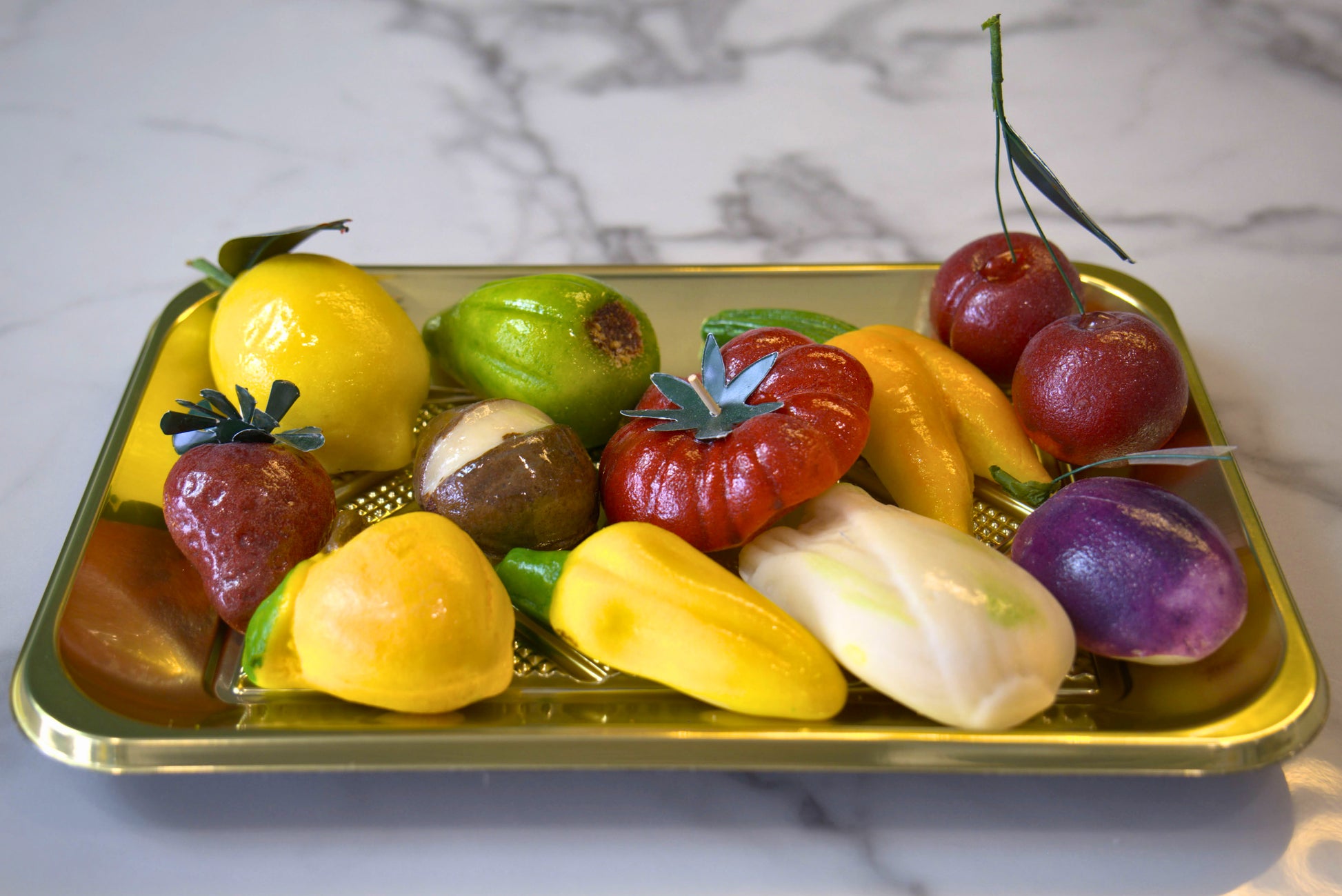 Assortment of marzipan in fruit shapes arranged on a golden tray from La Roma Pastry Shop