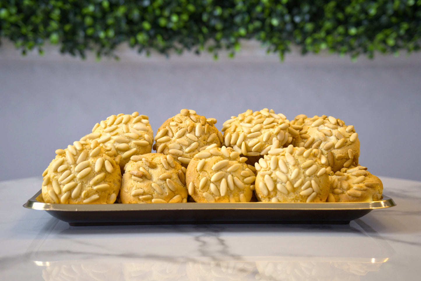 Tray of Pignoli Pine Nut Cookies from in front of greenery background from La Roma Pastry Shop