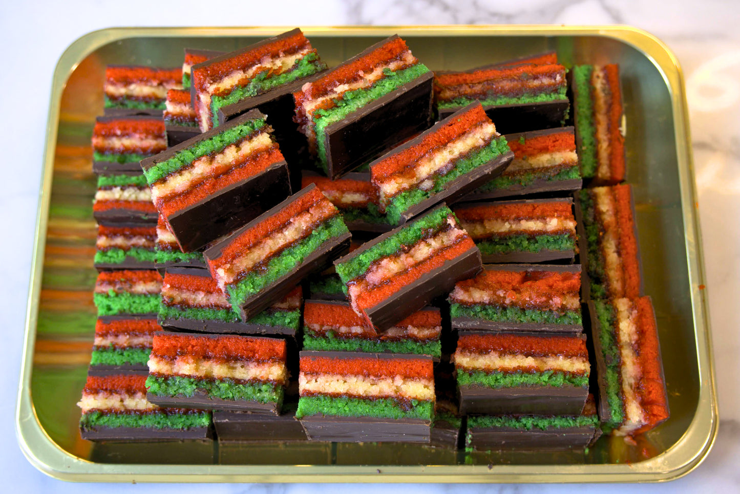 Overhead image of a golden tray of rainbow cookies made by La Roma Pastry Shop