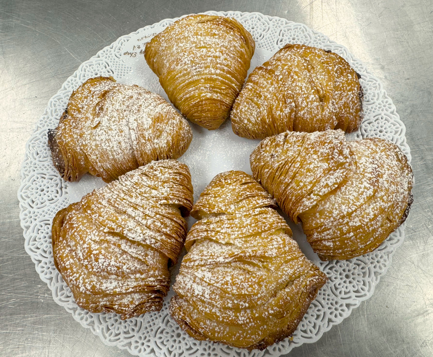 Ornate tray displaying six sfogliatelle in a circle dusted with powdered sugar