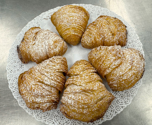 Ornate tray displaying six sfogliatelle in a circle dusted with powdered sugar