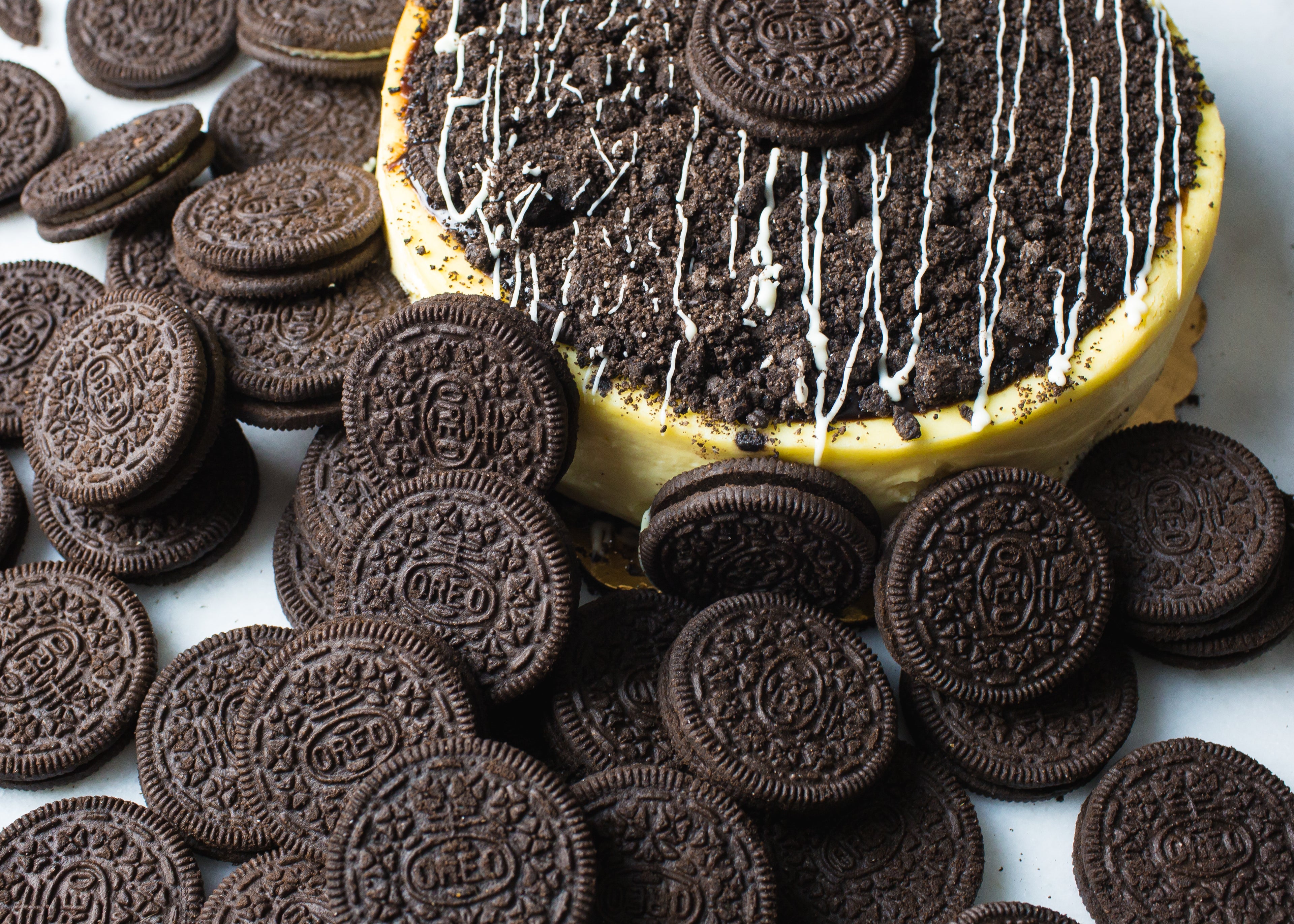 oreo cheesecake from la roma pastry shop in new york with many oreos scattered around and cookies crumbled on top with delicate frosted drizzle
