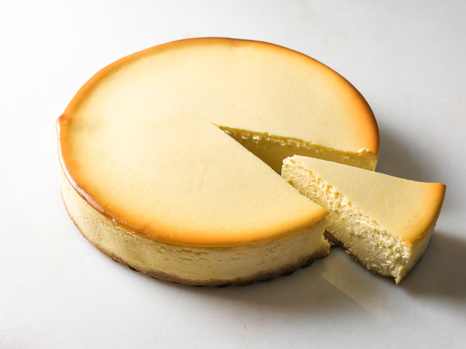classic original cream cheesecake with slice cut out made by la roma pastry shop in new york