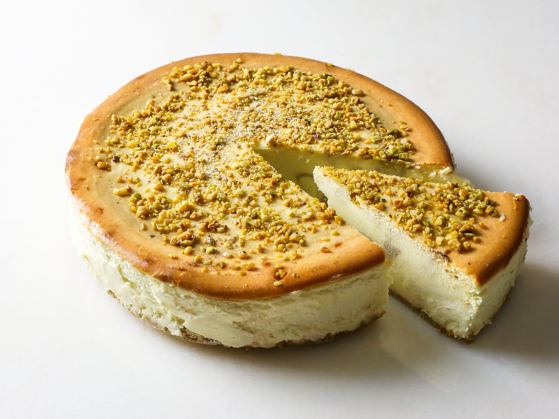 pistachio cheesecake with slice cut out made in new york by la roma pastry shop