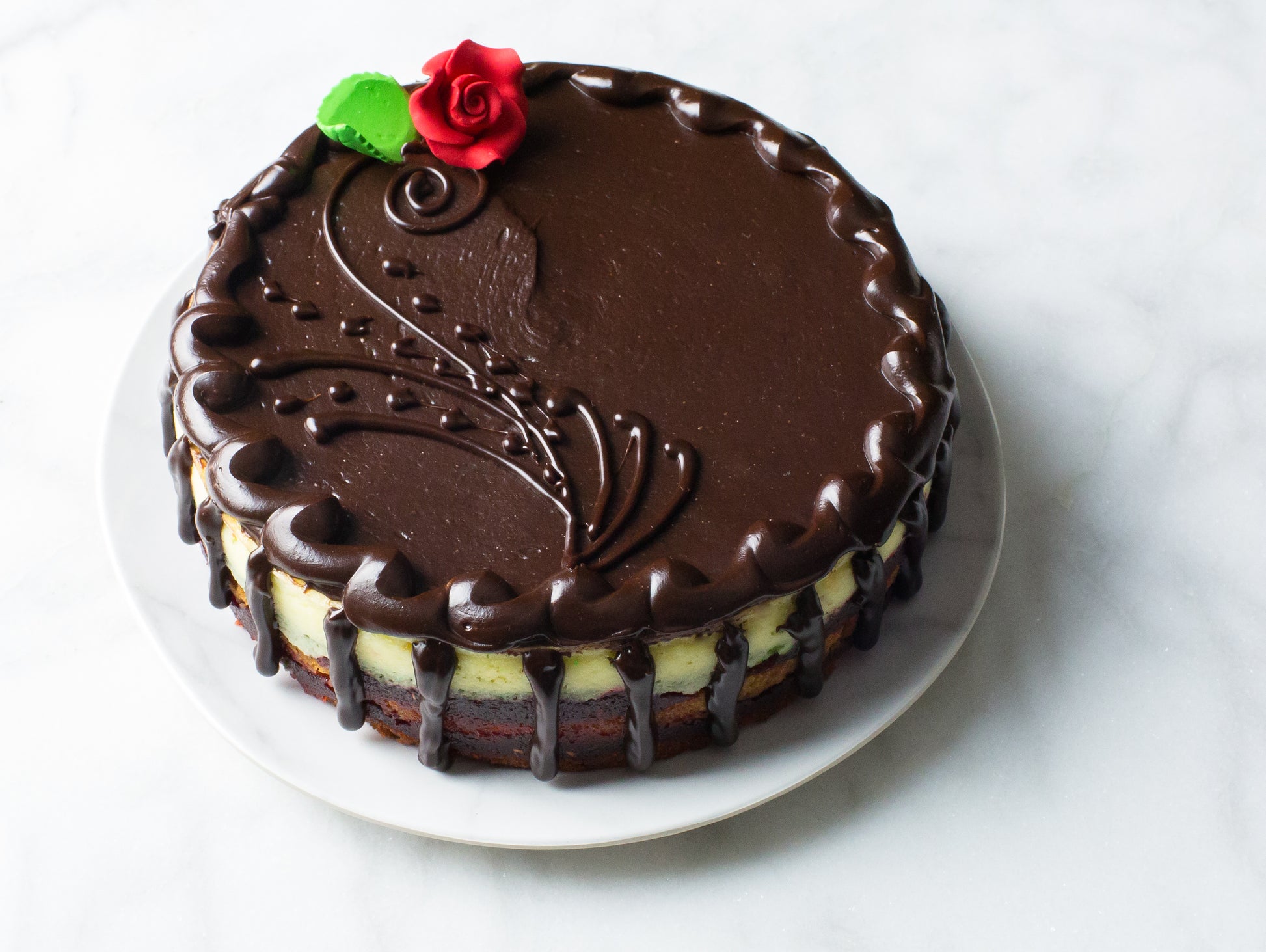 rainbow cookie cheesecake with chocolate and frosted rose made by long island bakery la roma pastry shop