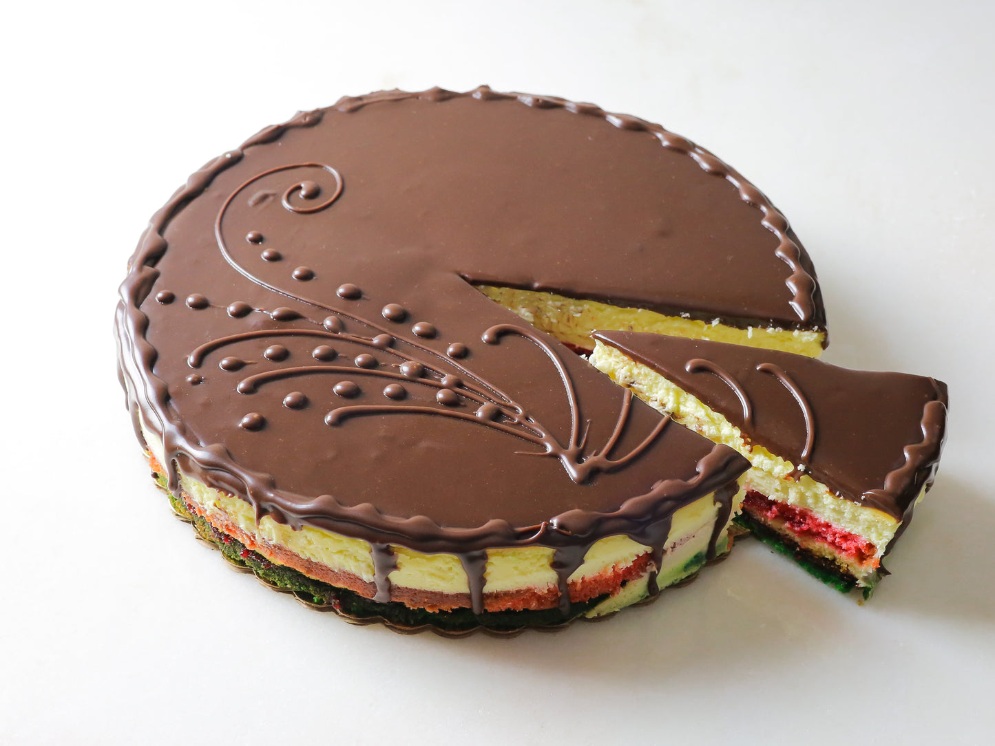 rainbow cookie cheesecake with slice cut out to reveal red white and green cake inside made by la roma pastry shop in oakdale new york