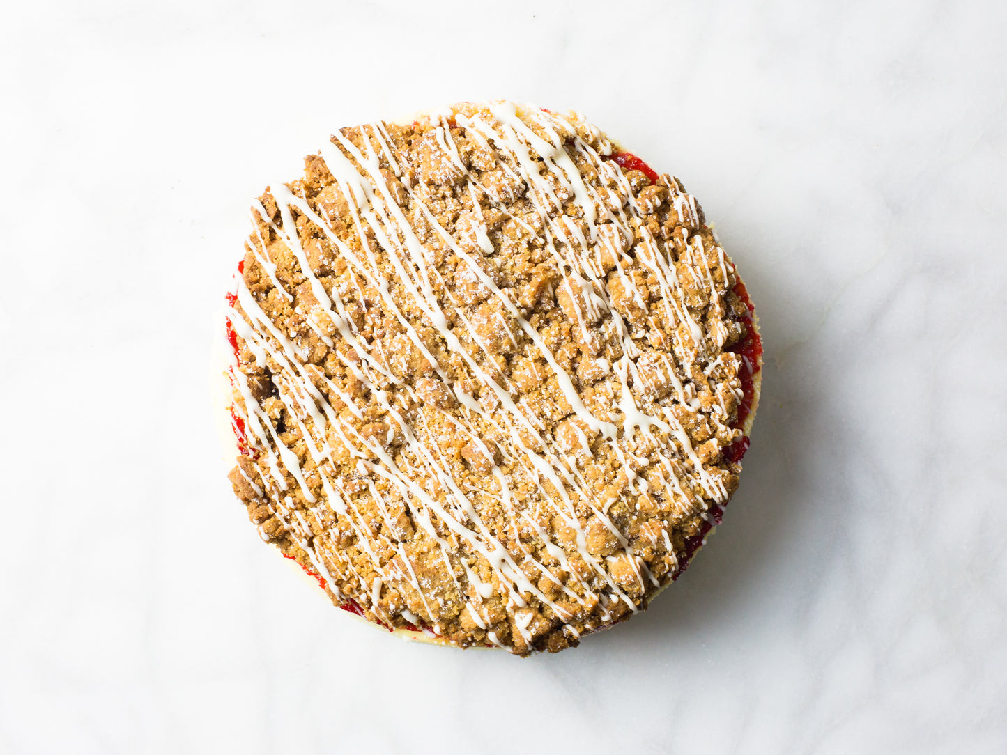 raspberry crumb cheesecake from overhead to see drizzled glaze made by la roma pastry shop in new york