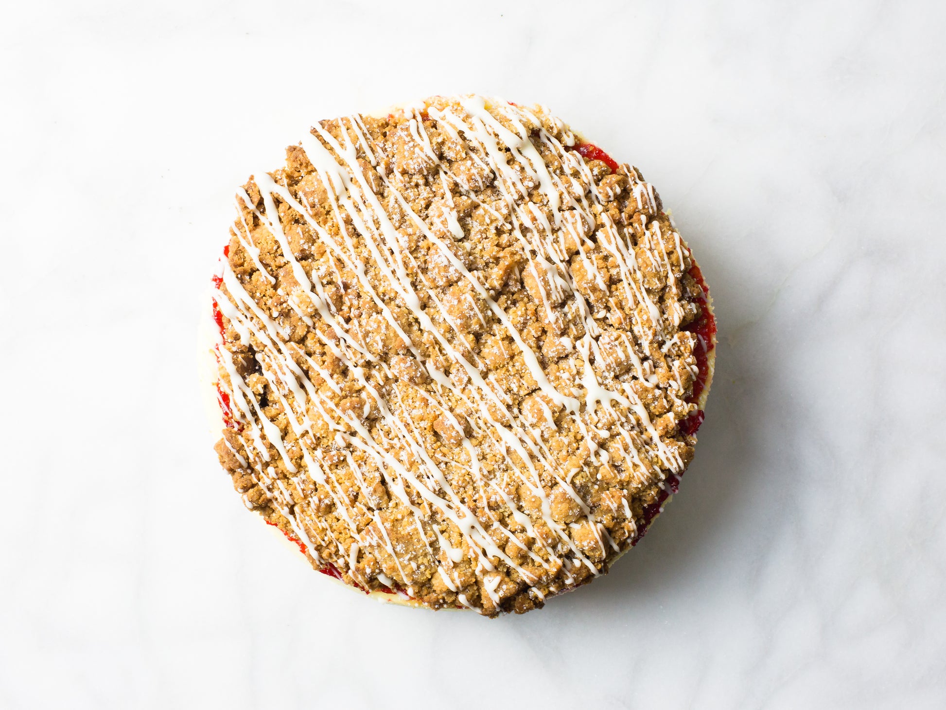 raspberry crumb cheesecake from overhead to see drizzled glaze made by la roma pastry shop in new york