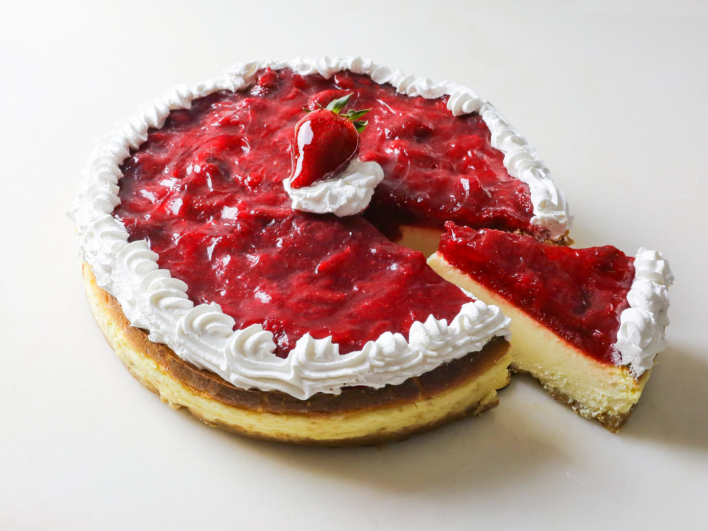 glistening strawberry cheesecake topped with glazed berries and whipped cream sliced into made on long island new york by la roma pastry shop